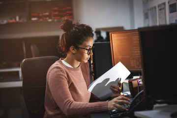 female programmer working on new project.she working late at night in her office.