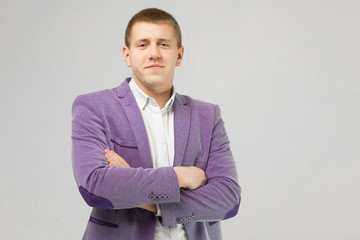 young man in a jacket folded arms isolated on light background