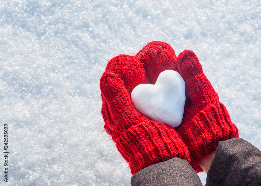 Female hands in knitted mittens with heart of snow in winter day. Love concept. Valentine day background. - obrazy, fototapety, plakaty 