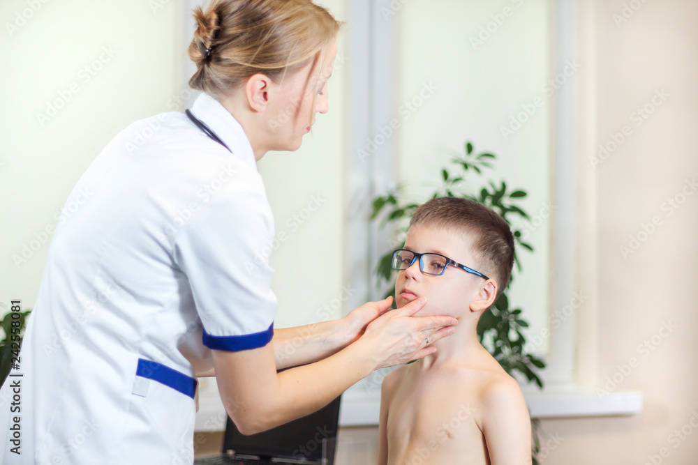 Lekarka w gabinecie lekarskim podczas badania migdałków u chłopca w okularach - obrazy, fototapety, plakaty 
