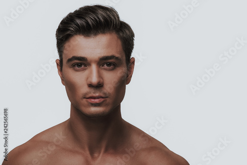 Fotografia, Obraz Close up of dark haired man standing against the grey background