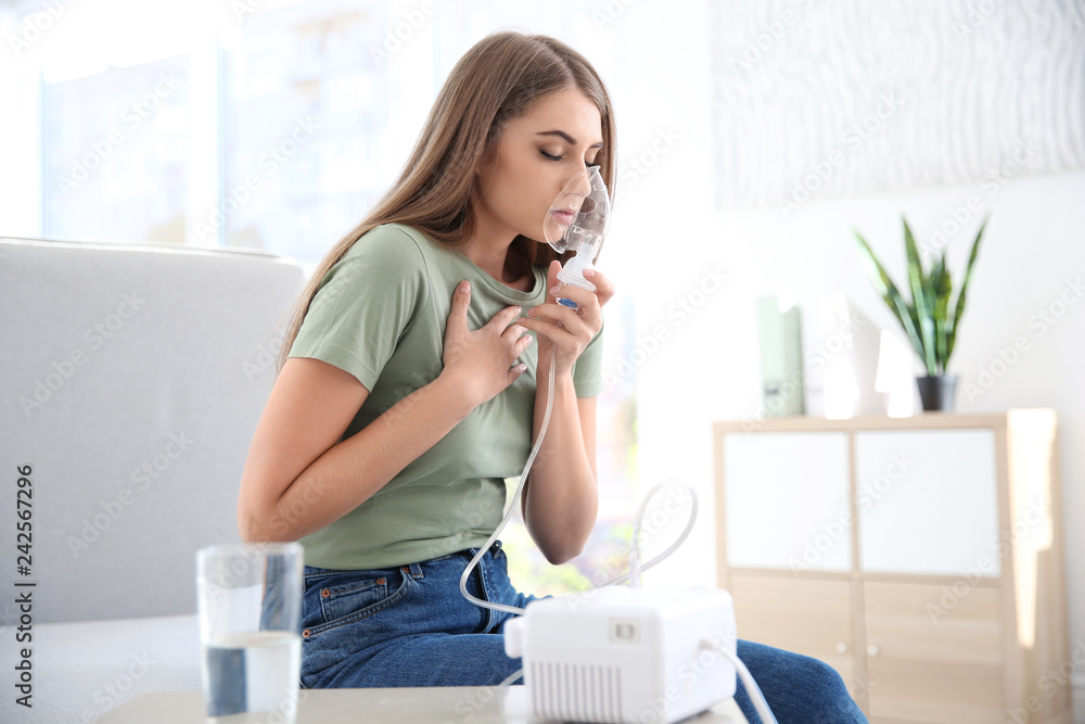 Young woman with asthma machine in light room - obrazy, fototapety, plakaty 