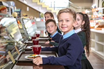 Children near serving line with healthy food in school canteen