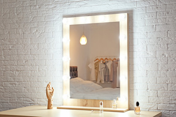 Makeup mirror on table near white wall in dressing room