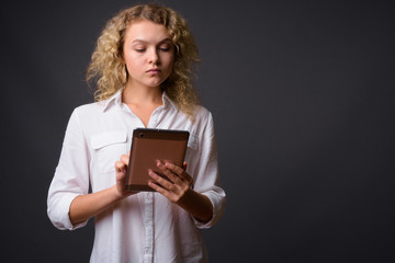 Wall Mural - Young beautiful businesswoman with curly blond hair against gray