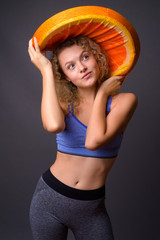 Wall Mural - Young beautiful woman holding big slice of orange fruit