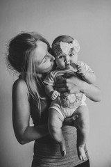 Happy mother and daughter. Mom holds on hands and kissing little baby girl, concept happy family, lifestyle. newborn. Photo shoot 4-5 months. flat lay. top view. Black and white photo.