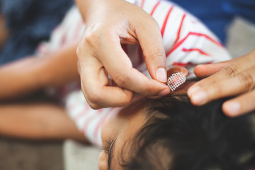 Parent helping her child perform first aid ear injury after she has been an accident