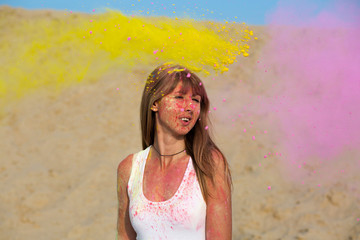 Splendid young woman wearing white t shirt, enjoying Holi festival at the desert