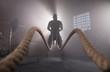© Lukas Gojda - Silhouette of man working out with battle ropes at gym.