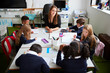 © Monkey Business - Elevated view of female primary school teacher sitting at table in a classroom with schoolchildren during a lesson