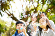© imtmphoto - little asian kids boy and girl sister and brother blowing bubbles in a park with parents watching from behind.