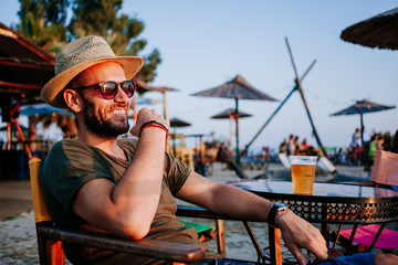 Sticker - Young man enjoying beer and sunset in a beach bar