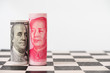 Close up US dollar banknote and Yuan banknote on chessboard with white background. USA and China have increase tax barrier for economy war trade.