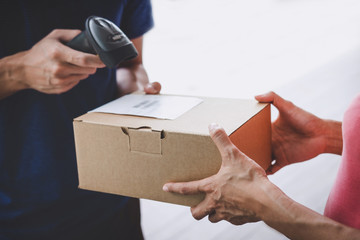 Wall Mural - Home delivery service and working service mind, Woman customer hand receiving a cardboard boxes parcel from service courier and deliveryman scan barcode to confirm delivery