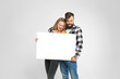 © Богдан Перфильев - young loving couple, bearded man and blondie are smiling, hugging, holding blank banner, isolated on white background, Advertisement concept. Mockup for design