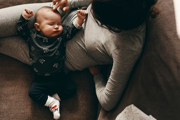 overhead view of a baby sleeping in the lap of his mother