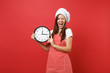 Housewife female chef cook or baker in striped apron, white t-shirt, toque chefs hat isolated on red wall background. Smiling woman holding in hand round clock hurry up. Mock up copy space concept.