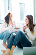 © karrastock - Two women eating fruit and drinking tea at home