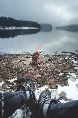 Fotografie, Obraz Close up view of fashion male legs wearing hiking boots sitting around a campfir