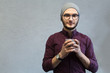 © Lalandrew - Young hipster guy enjoying aromatic coffee over white textured background. Dressed with shirt and grey hat, wearing glasses.
