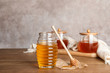 Glass jar with tasty honey and dipper on wooden table