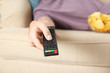 © New Africa - Man with remote control watching TV on sofa, closeup
