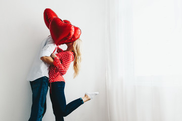 Couple. Love. Valentine's day. Emotions. Man and woman are kissing behind the red heart-shaped balloons