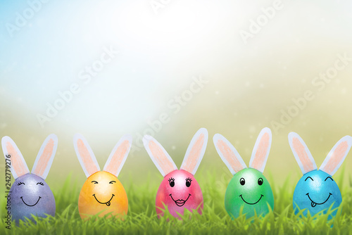 Fotografia A row of Easter eggs with smiles in fresh green grass. A banner