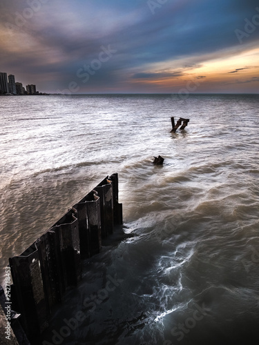 Foto A dramatic sunset photo with corrugated weathered steel piles or pilings sticking out of the choppy water and waves of Lake Michigan in Chicago