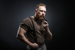 © Fotokvadrat - Lumberjack brutal red beard muscled man in brown shirt with smoking tube standing on dark background