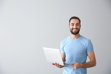 young freelancer with laptop on light background