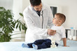 Male doctor working with cute little boy in clinic