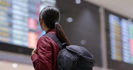 Poster - Tourist woman look at the flight number display board in the airport