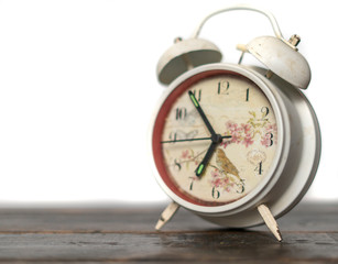 white retro alarm clock idolated on colorful background on wood surface b