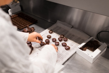 sweets production and industry concept - confectioner or worker packing candies at confectionery shop