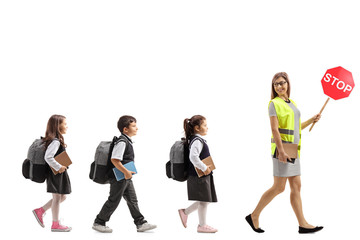 Wall Mural - School teacher with a safety vest and stop sign walking with schoolchildren