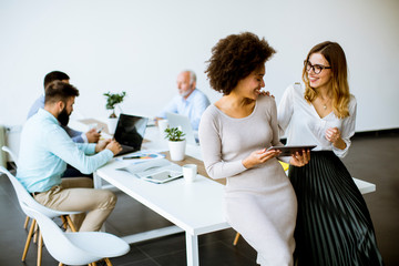 Two young businesswomen with a tablet in the office