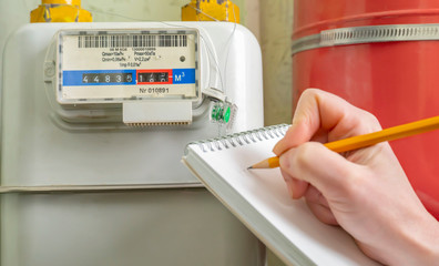 person writes indication gas meter in notebook.