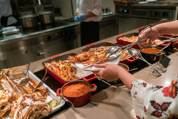 Wall Mural - Woman hand choosing Grilled Lobster in the buffet