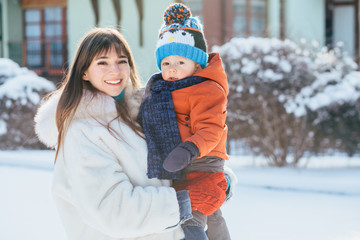 Winter holidays outdoor portrait concept.. Warm clothes. Family portrait. concept. Adorable mother and toddler son have fun togtether outside in sunny frosrty day. Copy space