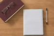 © layue - Closed book with blank notebook and glasses on wooden background.