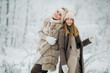 © snedorez - Portrait of two happy blonde women in hat on walk in winter forest