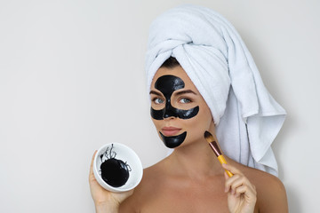 Young and beautiful woman with black peel-off mask on her face