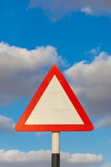 Blank triangle road sign with a blue sky and cloudy background. Conceptual.