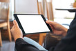© Farknot Architect - Mockup image of a woman holding black tablet pc with blank white screen horizontally while sitting in cafe