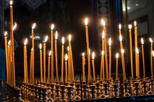 Many burning wax candles in the orthodox church or temple