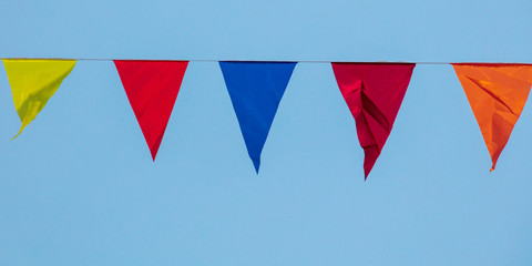 multicolored flags for holidays against the blue sky