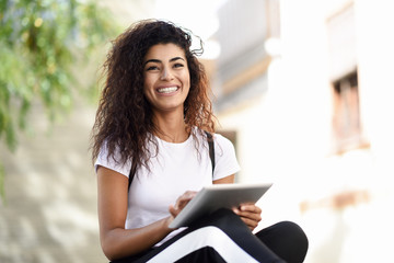 smiling african woman using digital tablet outdoors