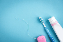 Tooth Paste, Brush And Dental Floss On Blue Background. Cleaning And Protection Of Teeth 